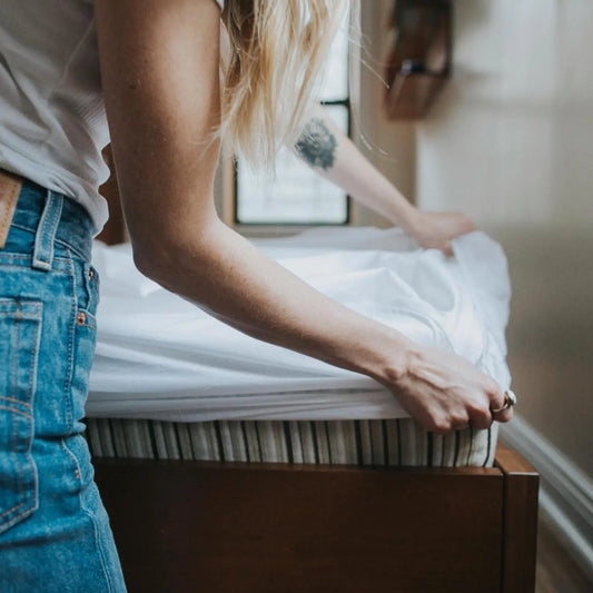 Woman putting Essentia GOTS certified organic cotton sheets on her mattress