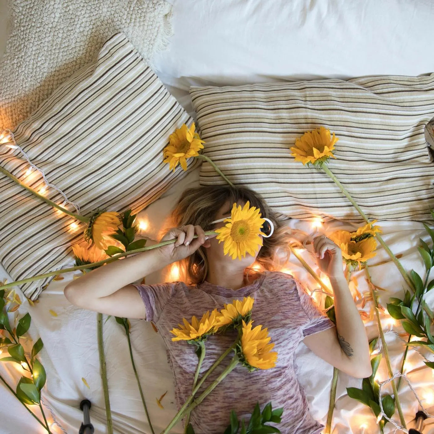 Woman with sunflowers surrounded by Essentia comfort pillows